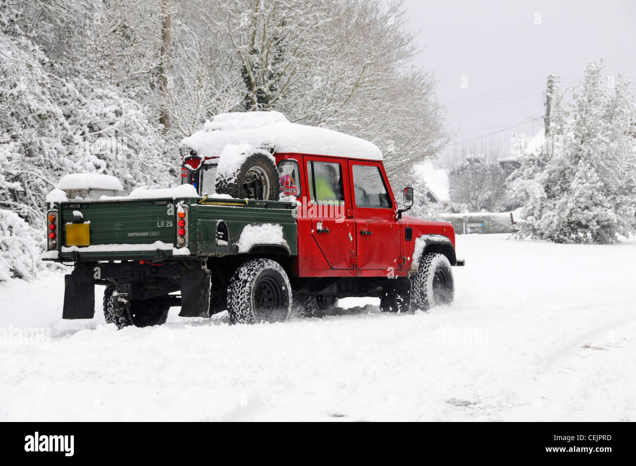 Scena di neve Land Rover Defender 130 4x4 alla guida del raccoglitore sul paese strette corsie a nevicate invernali il freddo Brentwood Essex England Regno Unito Foto Stock