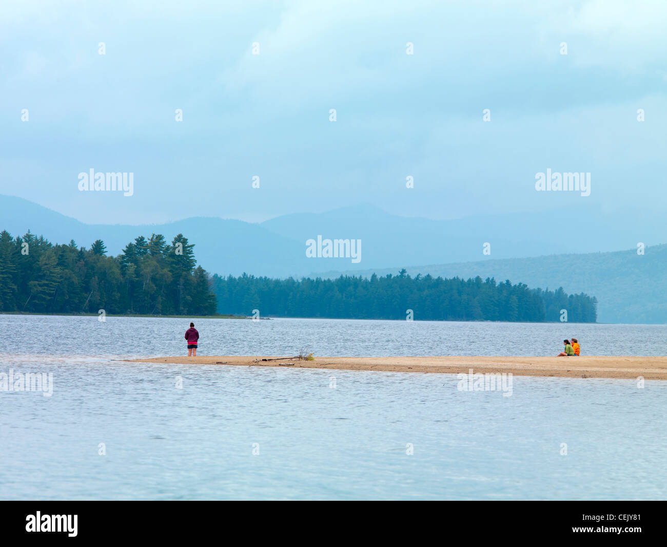 Tre giovani donne pesce da uno spiedo di sabbia su Pine Island in si restringe di Richardson Lago in western Maine. Foto Stock