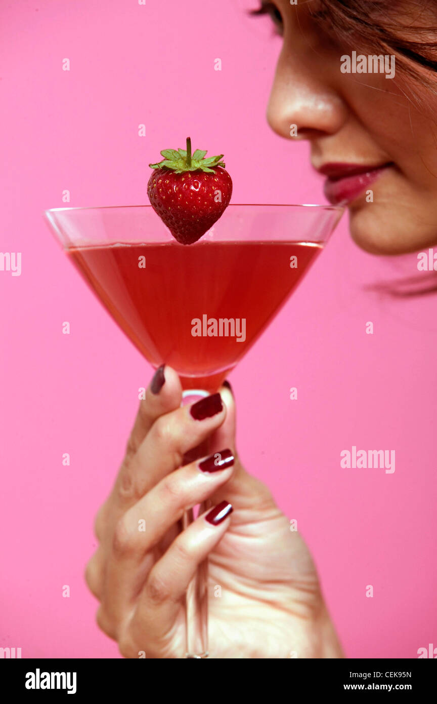 Ricci femmina brunette capelli, rosso scuro lip gloss e rosso scuro smalto per unghie, indossando viola scuro abito spalline sottili, in piedi Foto Stock