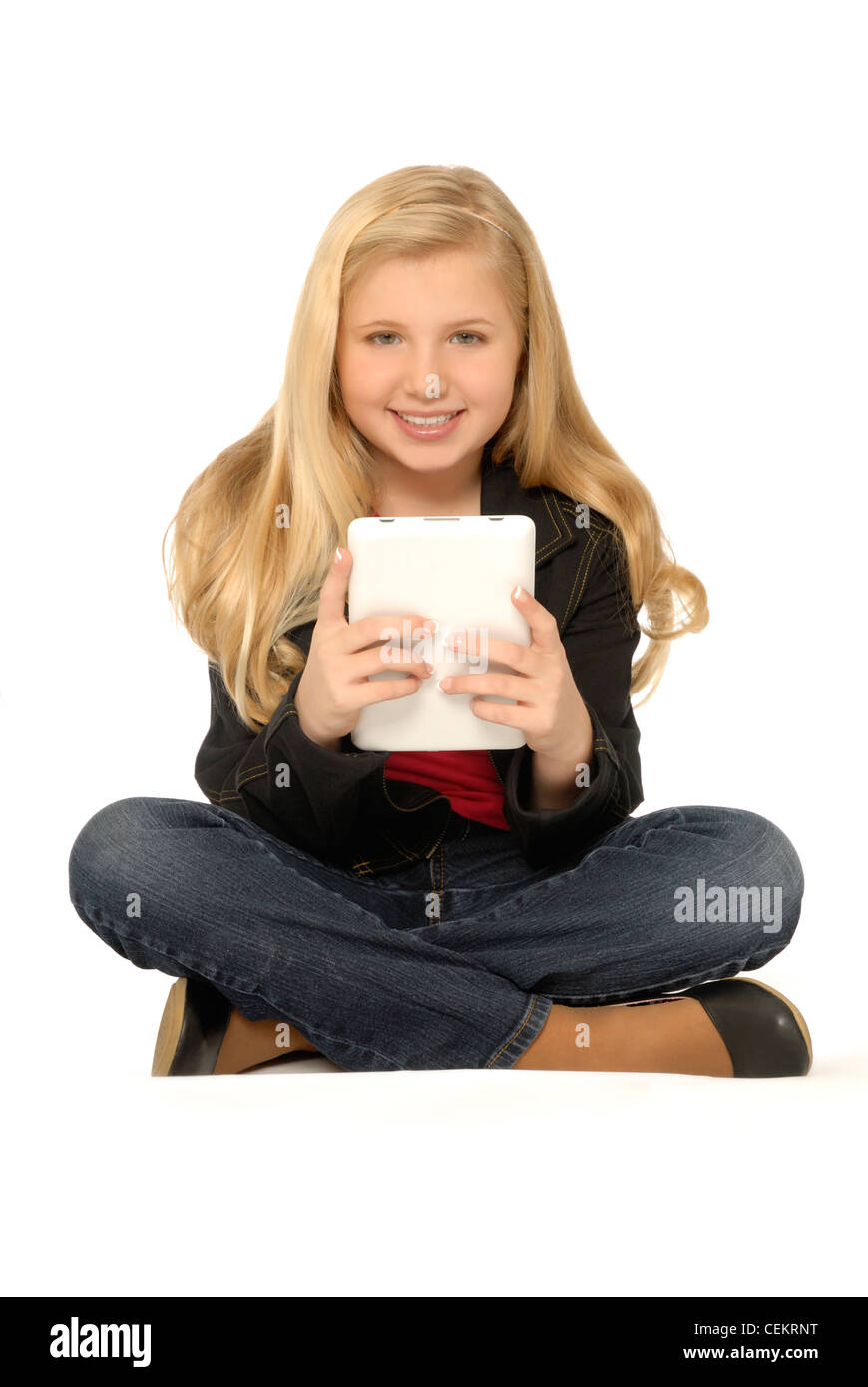 Dieci anni di ragazza seduta e utilizzando un computer tablet. Lei è sempre sorridente e guardando il visore. Foto Stock