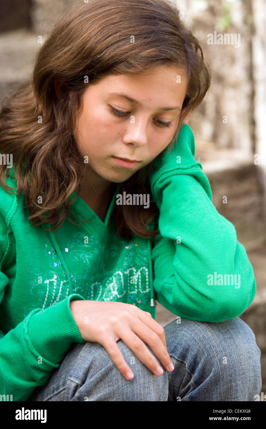 Azienda femmina guardando il suo ginocchio con la testa appoggiata sulla sua mano Foto Stock