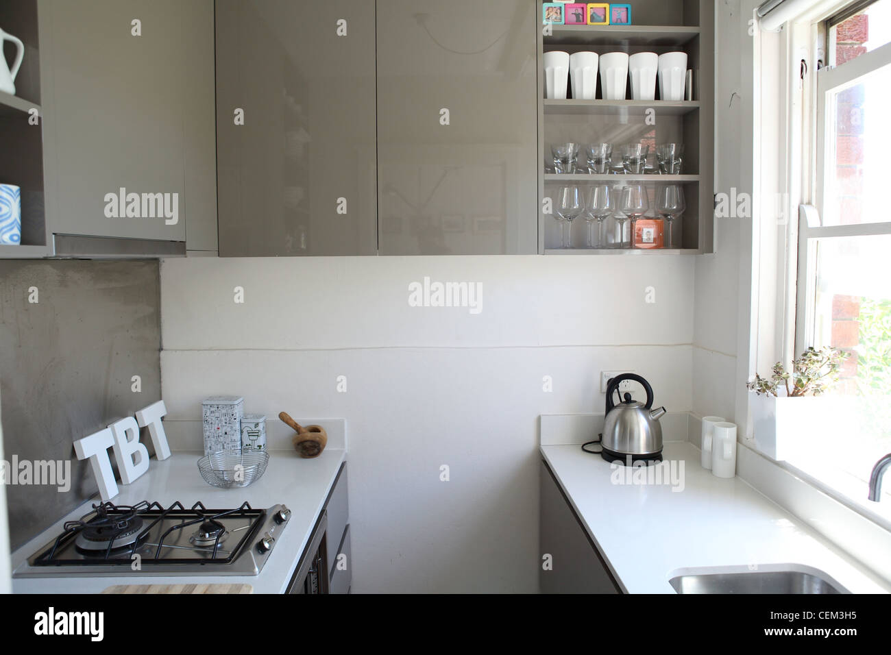 Appartamento in Sydney piccola cucina galley con pietra bianca le superfici di lavoro e lucido grigio armadi Foto Stock