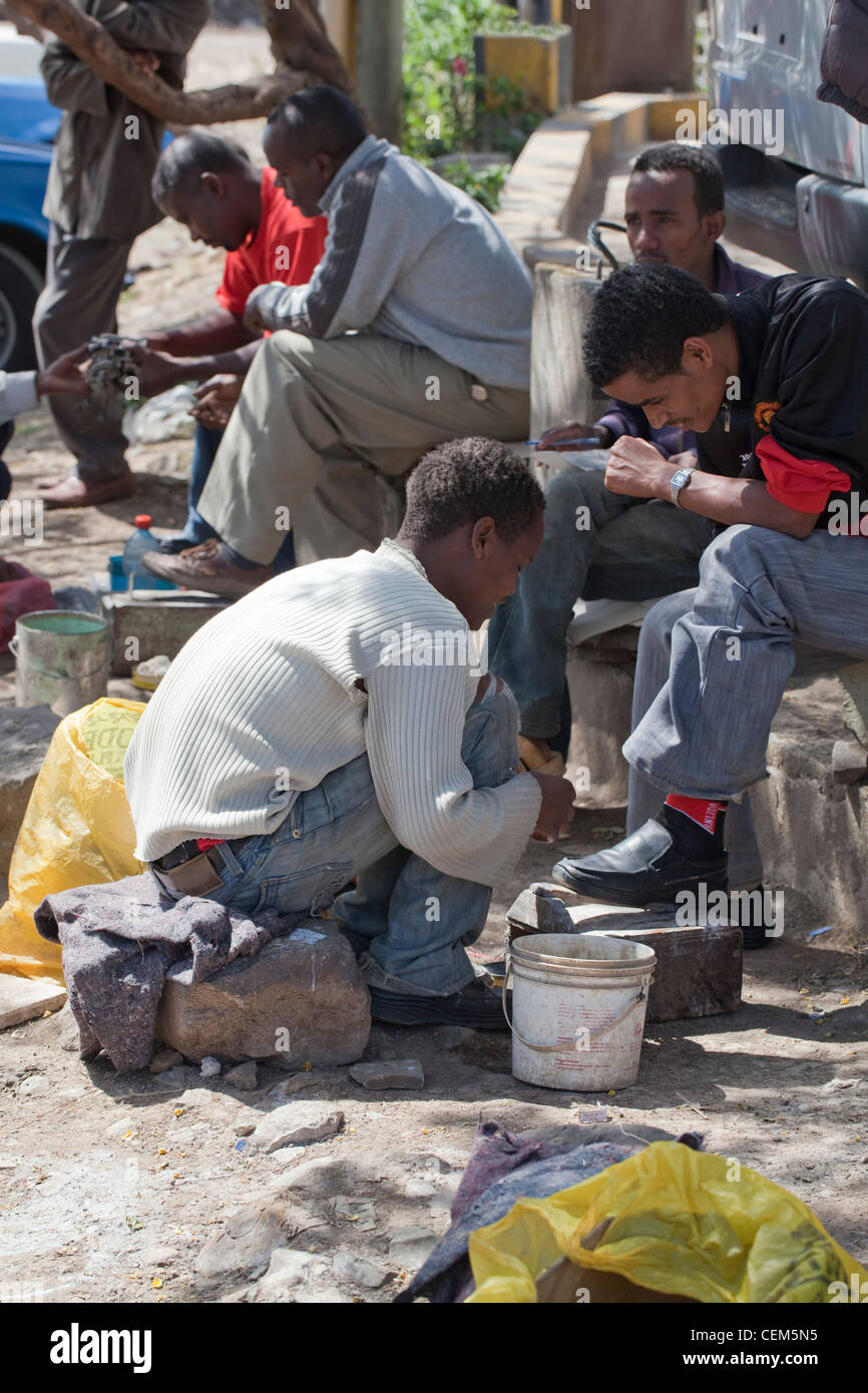 Etiopia ad Addis Abeba. 'Shoe shine boy". Giovane uomo per la pulizia e la lucidatura delle scarpe in cuoio di gente seduta sulla città del lato strada. Foto Stock