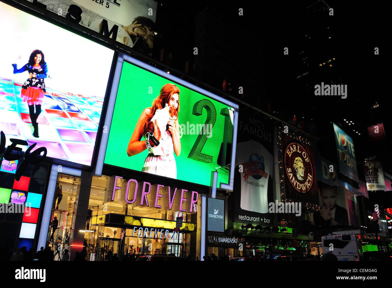 Night view, verso West 45th Street, schermi LED femmina sopra le immagini Disney Store per sempre 21 Boutique, 7th Avenue, New York Foto Stock