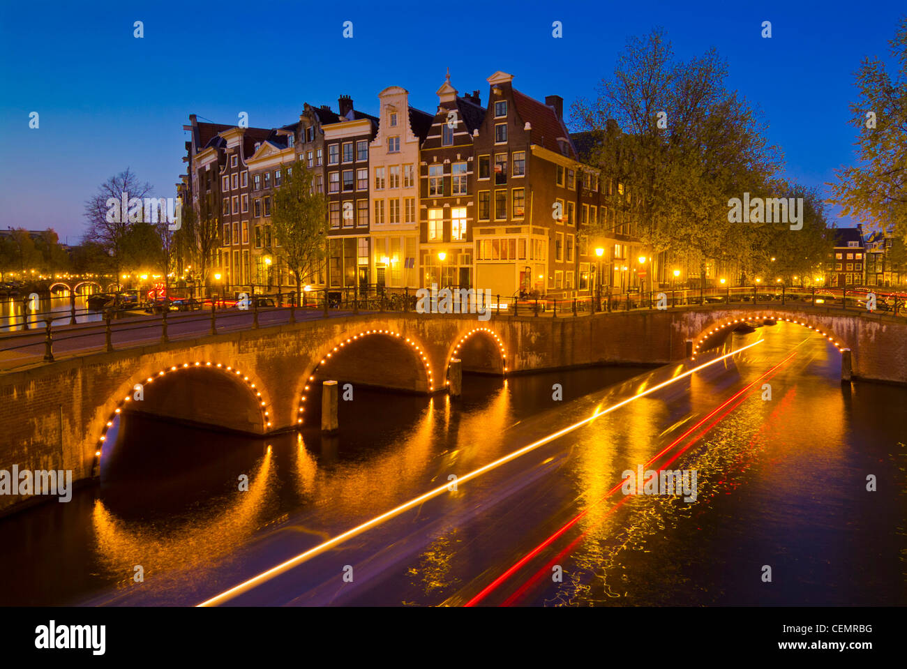 Canal tour barca lasciando sentieri di luce sotto i ponti sul canale Keizersgracht Amsterdam Paesi Bassi Olanda UE Europa Foto Stock
