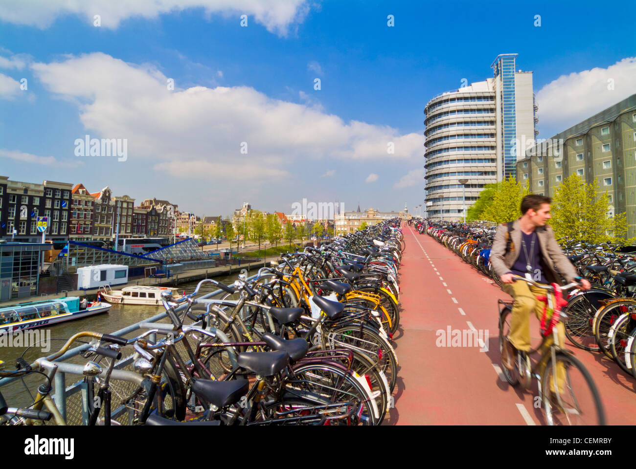 Ciclista in cerca di un posto per parcheggiare la sua bicicletta vicino alla stazione centrale di Amsterdam Paesi Bassi Olanda UE Europa Foto Stock