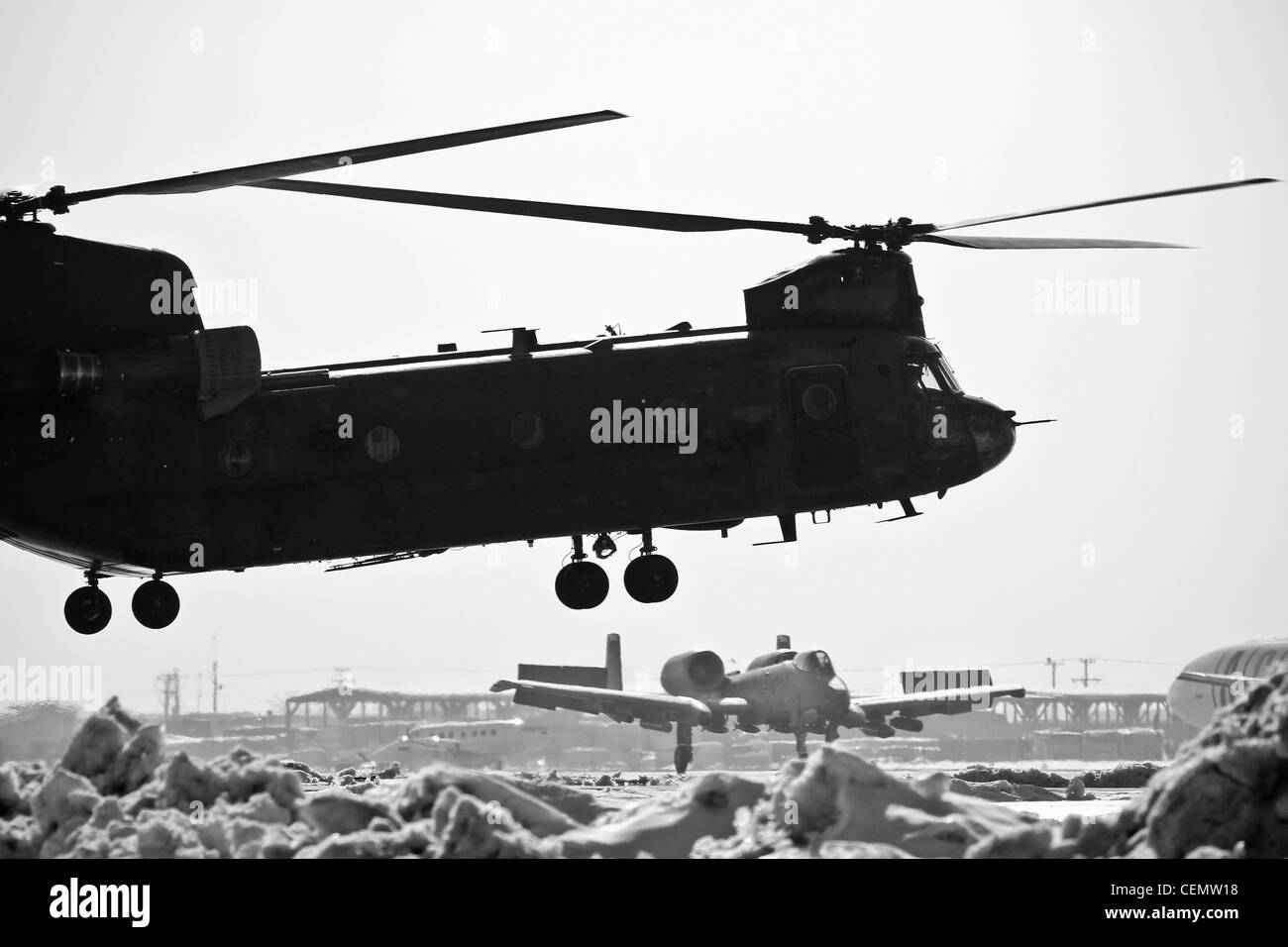 Un elicottero pesante Chinook dell'esercito degli Stati Uniti CH-47 è in piedi per il decollo come un US Air Force A-10C Thunderbolt II atterra a Bagram Air Field, Afghanistan, il 16 febbraio 2012. Foto Stock