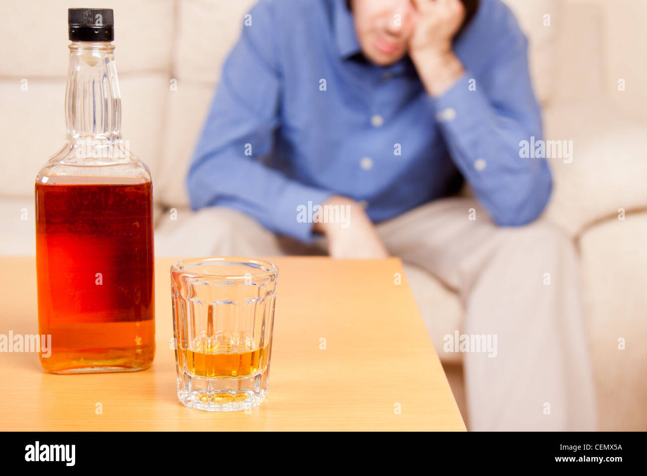 Giovane uomo alcolica di bere whisky nella sua casa. Foto Stock