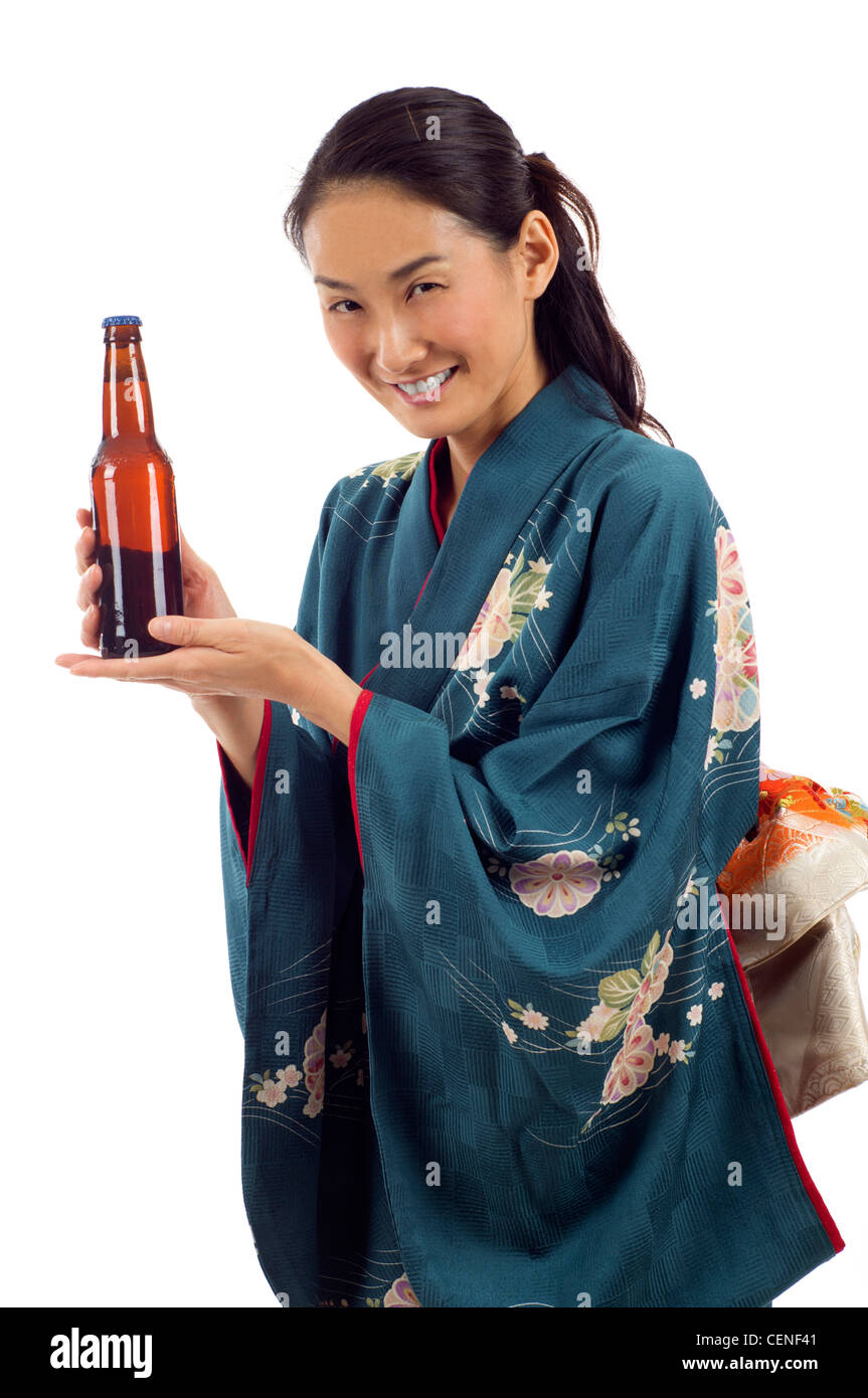 Attraente sorridente kimono donna in possesso di una bottiglia di birra isolato su sfondo bianco Foto Stock