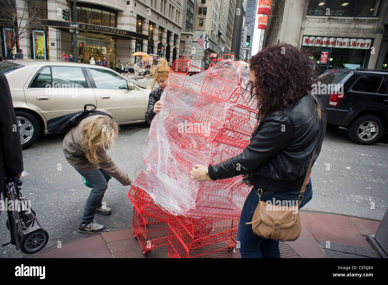 Le donne cercano di manovrare un carrello di cestelli per le strade della città Foto Stock