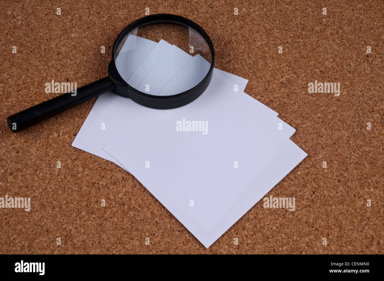 Lente d'ingrandimento e pila di carta su superficie in sughero – Office Research Flatlay Foto Stock