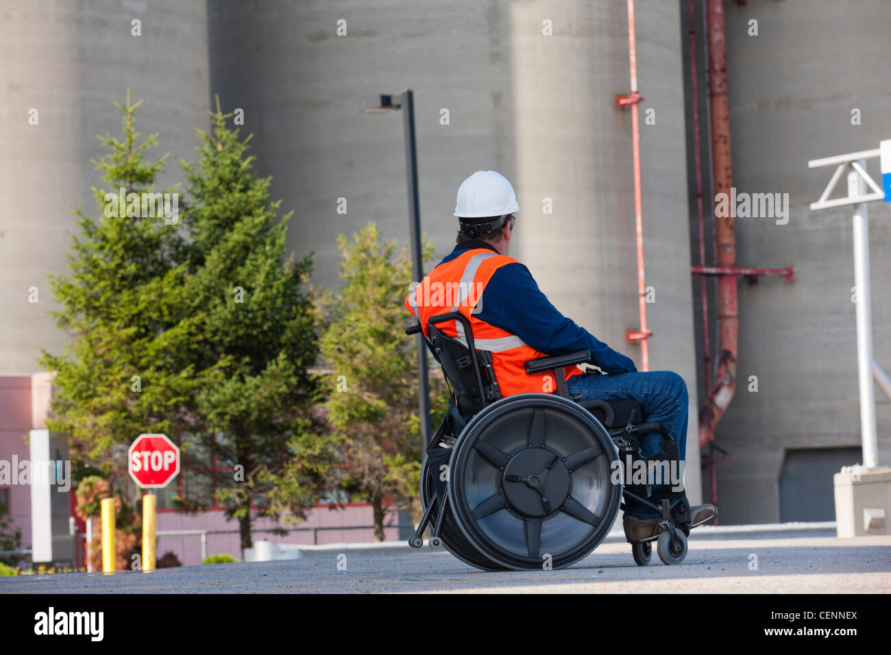 Facilities engineer in una sedia a rotelle a studiare all'aperto dei serbatoi di stoccaggio Foto Stock