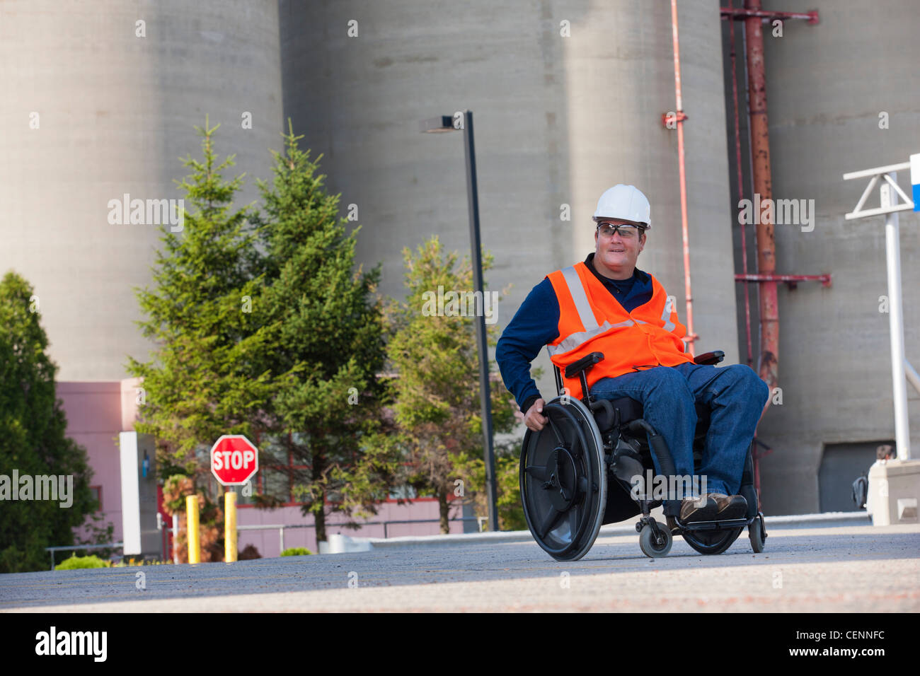Facilities engineer in una sedia a rotelle all'aperto di ispezione dei serbatoi di stoccaggio Foto Stock