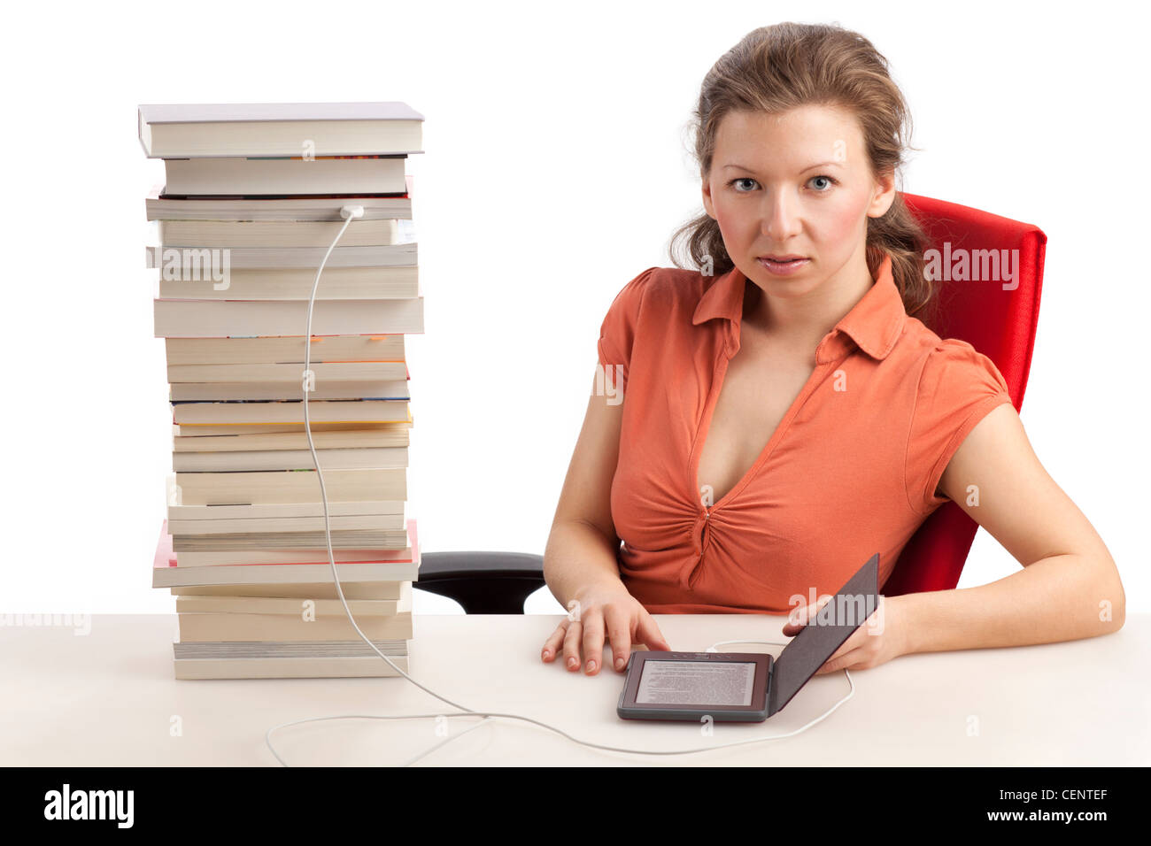 Giovane donna con lettore di ebook che è collegato con una pila di libri Foto Stock