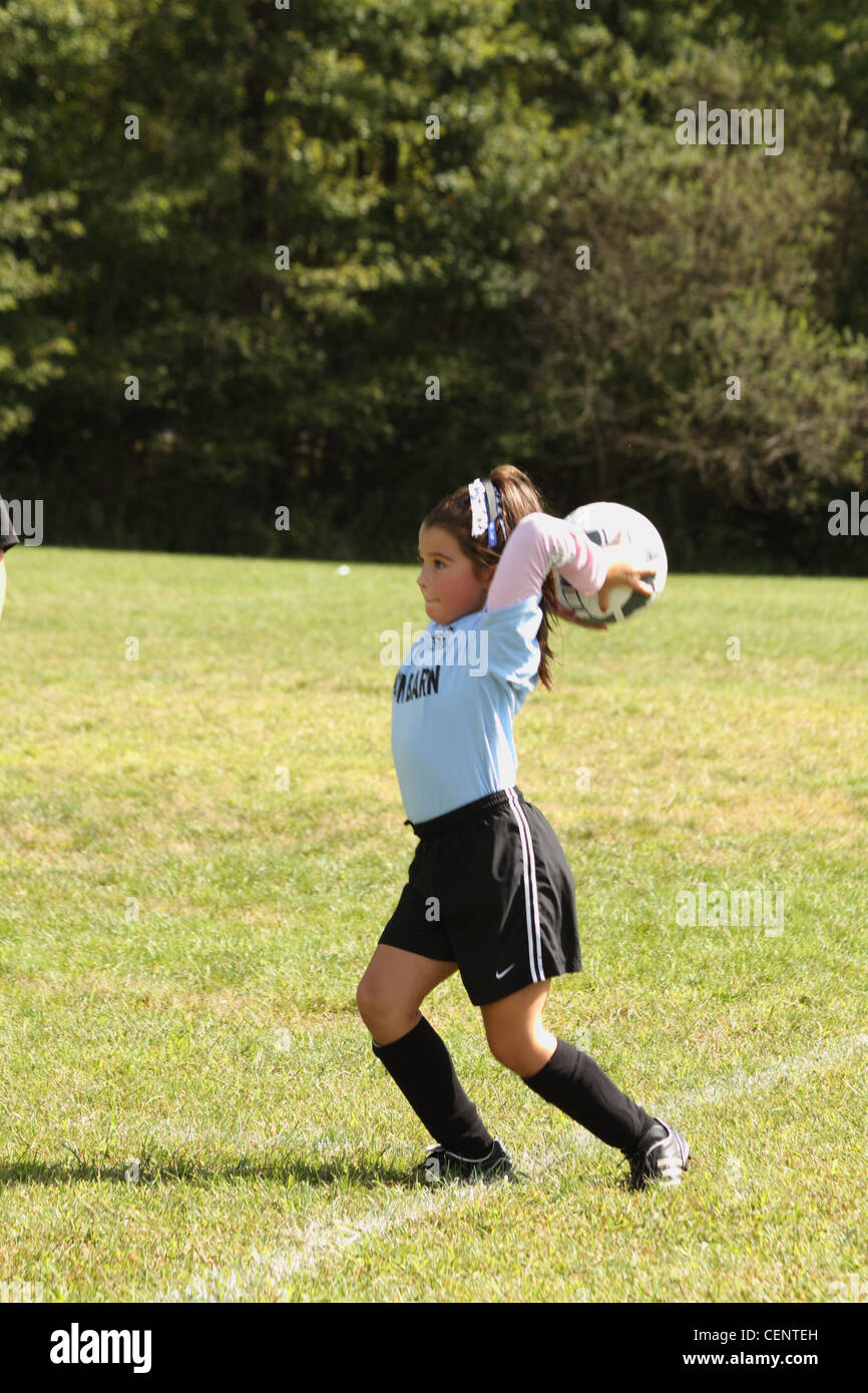 Ragazza che gioca a calcio nel lanciare in palla da linee laterali Foto Stock