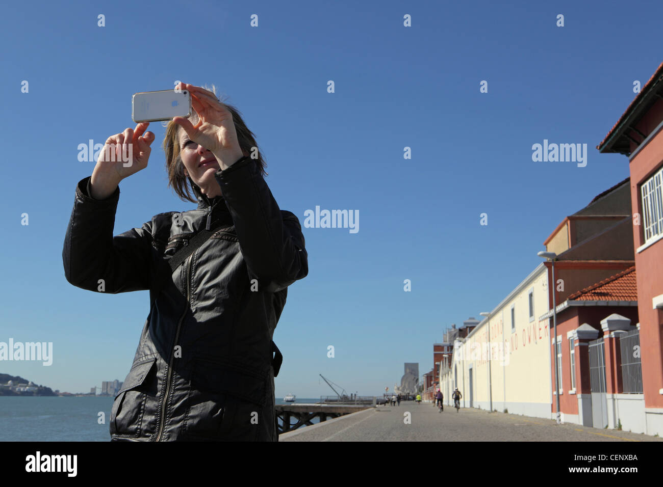 Donna turista femminile utilizza il suo bianco iPhone 4S a prendere le fotografie della sua vacanza presso il lungomare di Lisbona, Portogallo Foto Stock