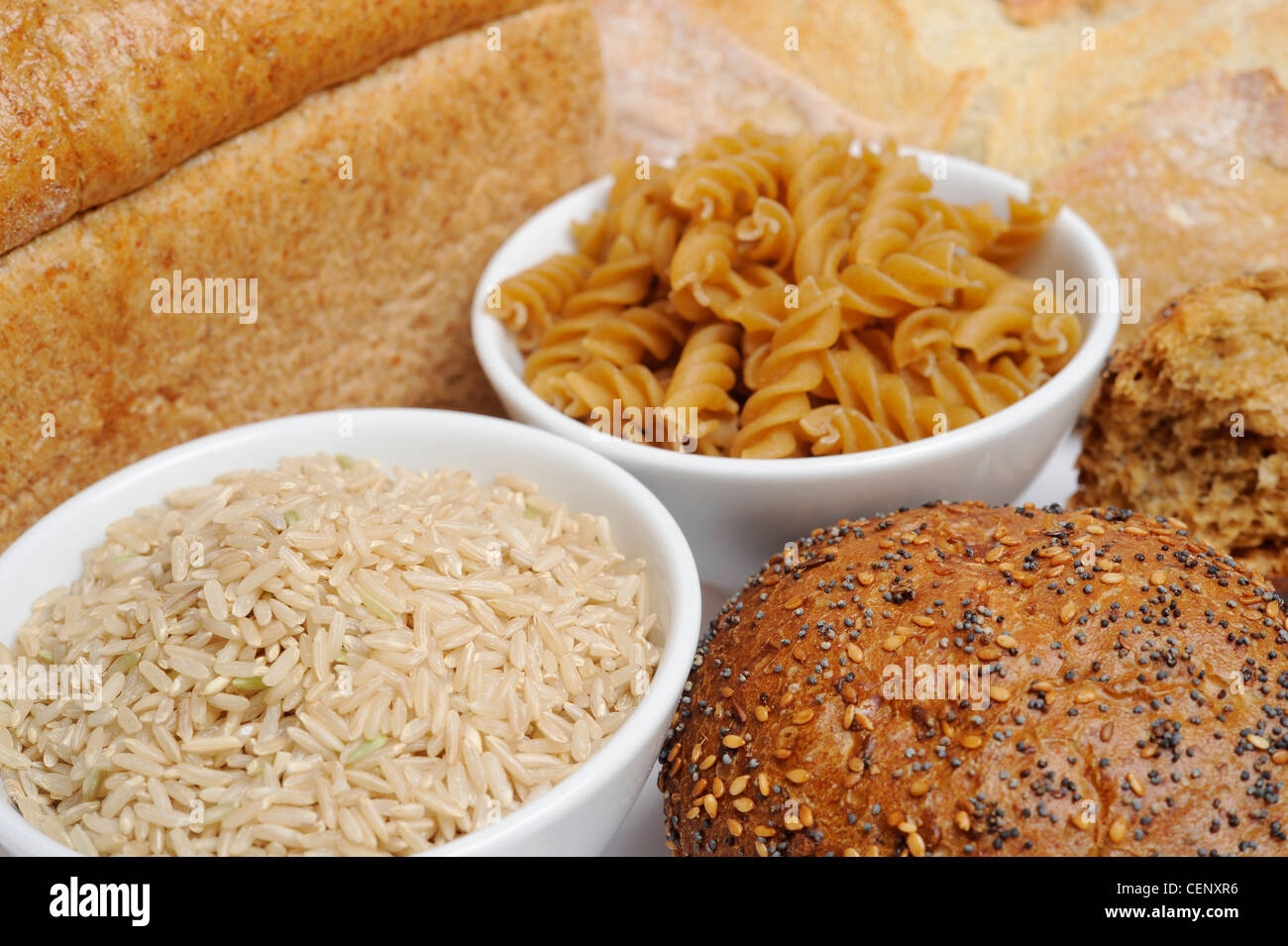 Due recipienti riempiti di riso a grani lunghi e essiccato fusilli circondato da pagnotte di pane Foto Stock