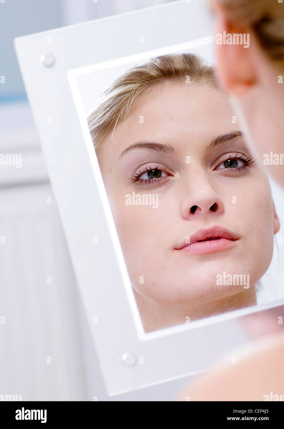 Femmina guardando il suo riflesso in uno specchio, Foto Stock
