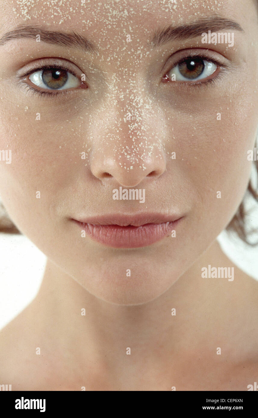 Femmina di applicazione a spruzzo di liquido alla fondazione T zone area, c'erano pochi sorrisi, guardando la fotocamera Foto Stock