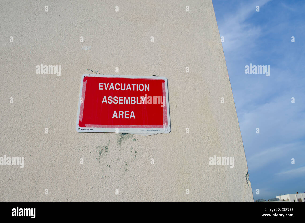 Rosso di evacuazione Area Assemblaggio segno fissato con nastro adesivo su una parete Foto Stock