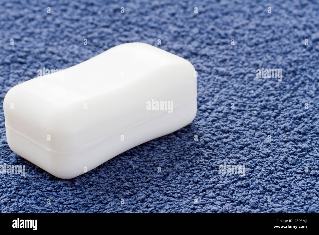 Barra di sapone bianco su blu asciugamano Foto Stock