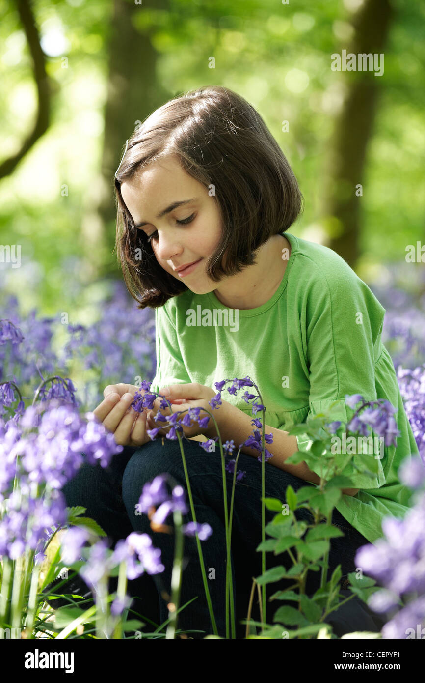 Giovane ragazza seduta in un bosco pieno di Bluebells. Foto Stock