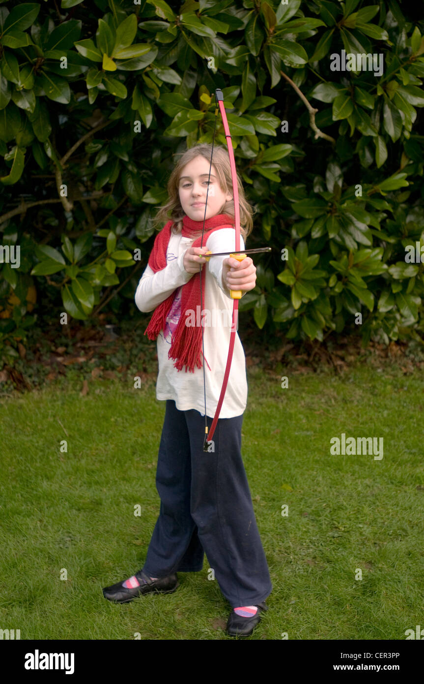 Un 9 anno vecchia ragazza gioca con un arco e frecce Foto Stock
