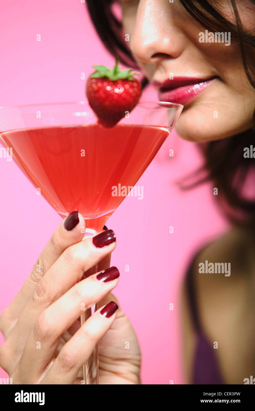 Ricci femmina brunette capelli, rosso scuro lip gloss e rosso scuro smalto per unghie, indossando viola scuro abito spalline sottili, in piedi Foto Stock