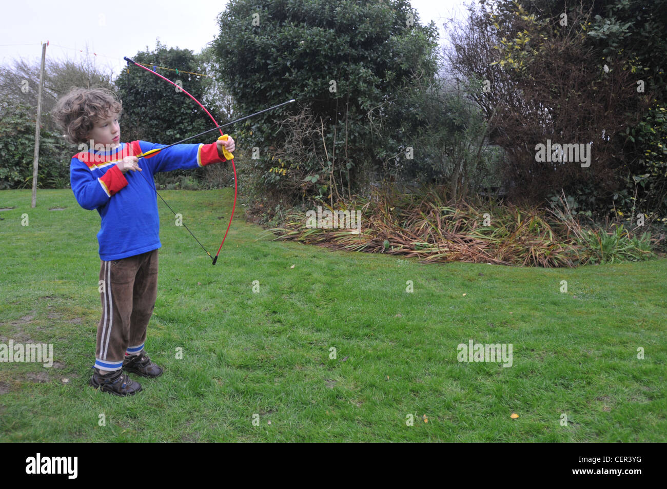 Un bambino di sei anni ragazzo gioca con un arco e frecce Foto Stock