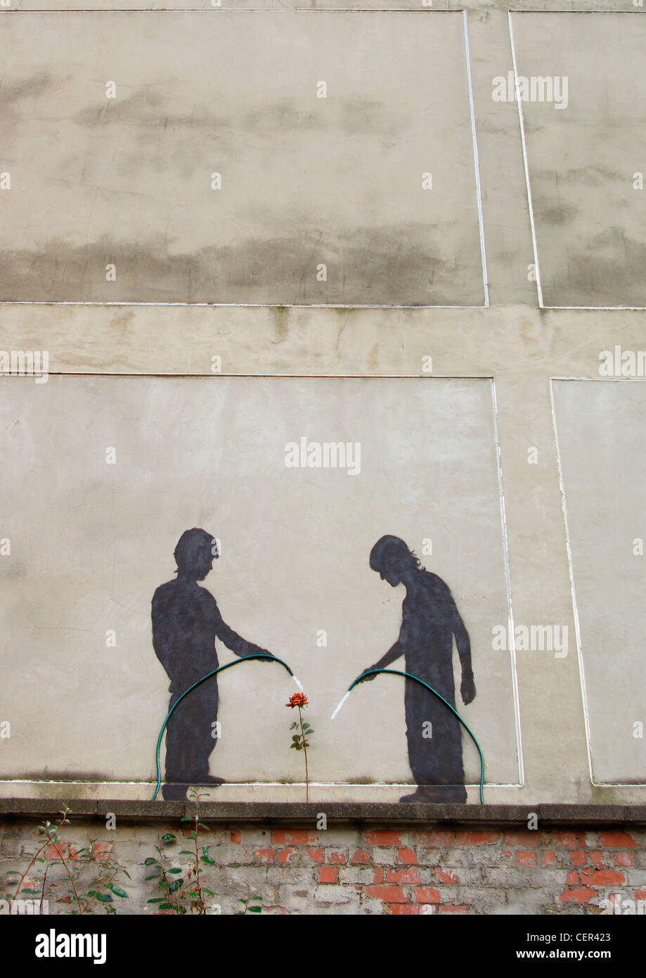 Arte Urbana di due bambini abbeveraggio un fiore. Foto Stock