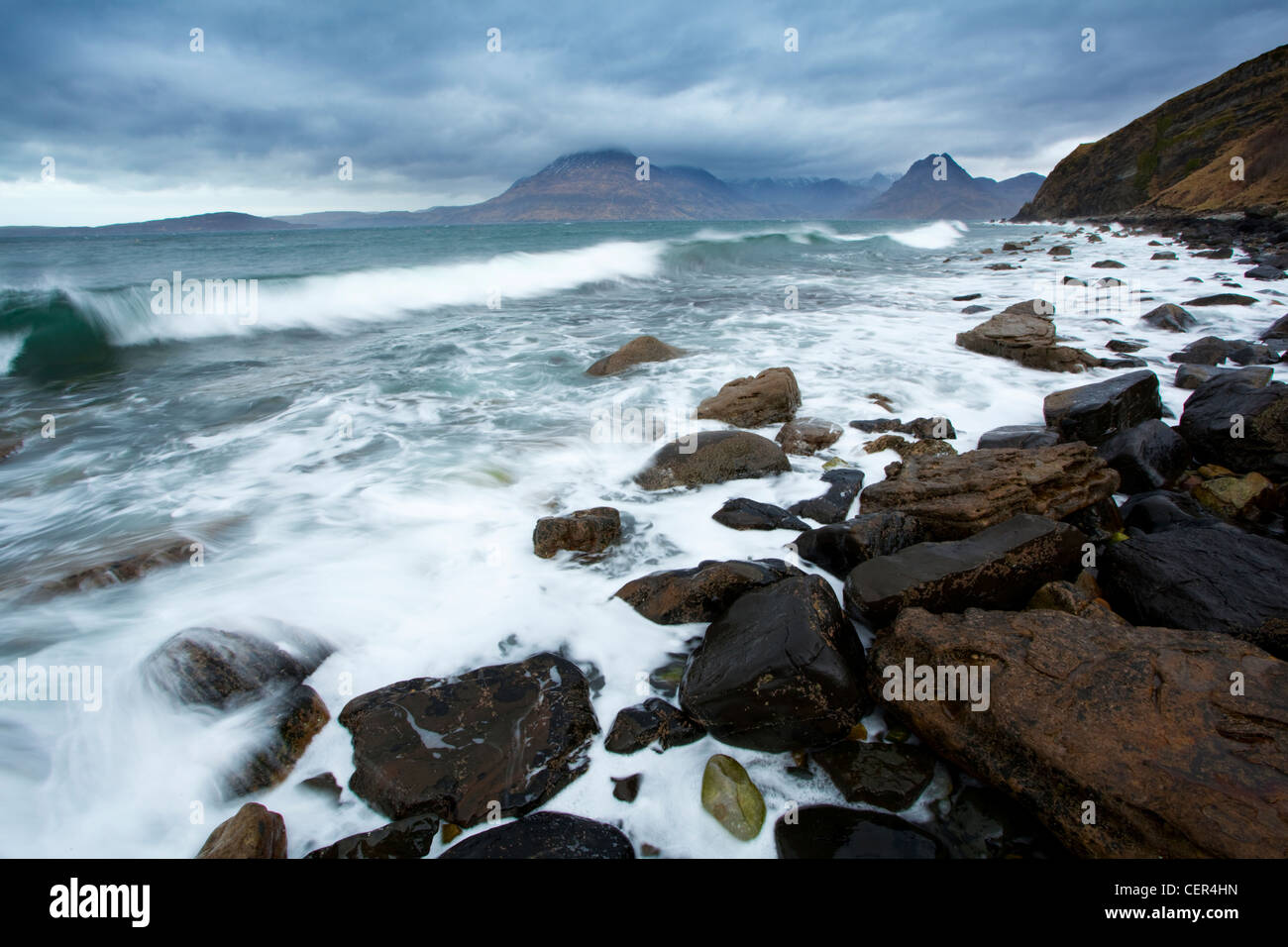 La laminazione delle onde sulla spiaggia rocciosa a Elgol sotto il cielo tempestoso sull'Isola di Skye. Foto Stock