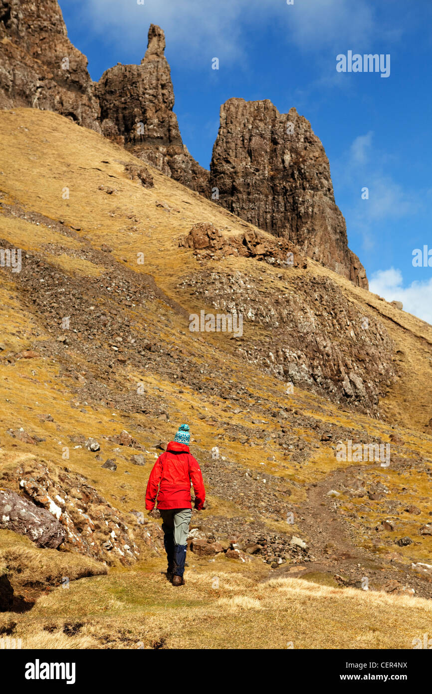 Una donna che indossa un impermeabile rosso camminando sul Quiraing, un antico smottamento sulla penisola di Trotternish. Foto Stock