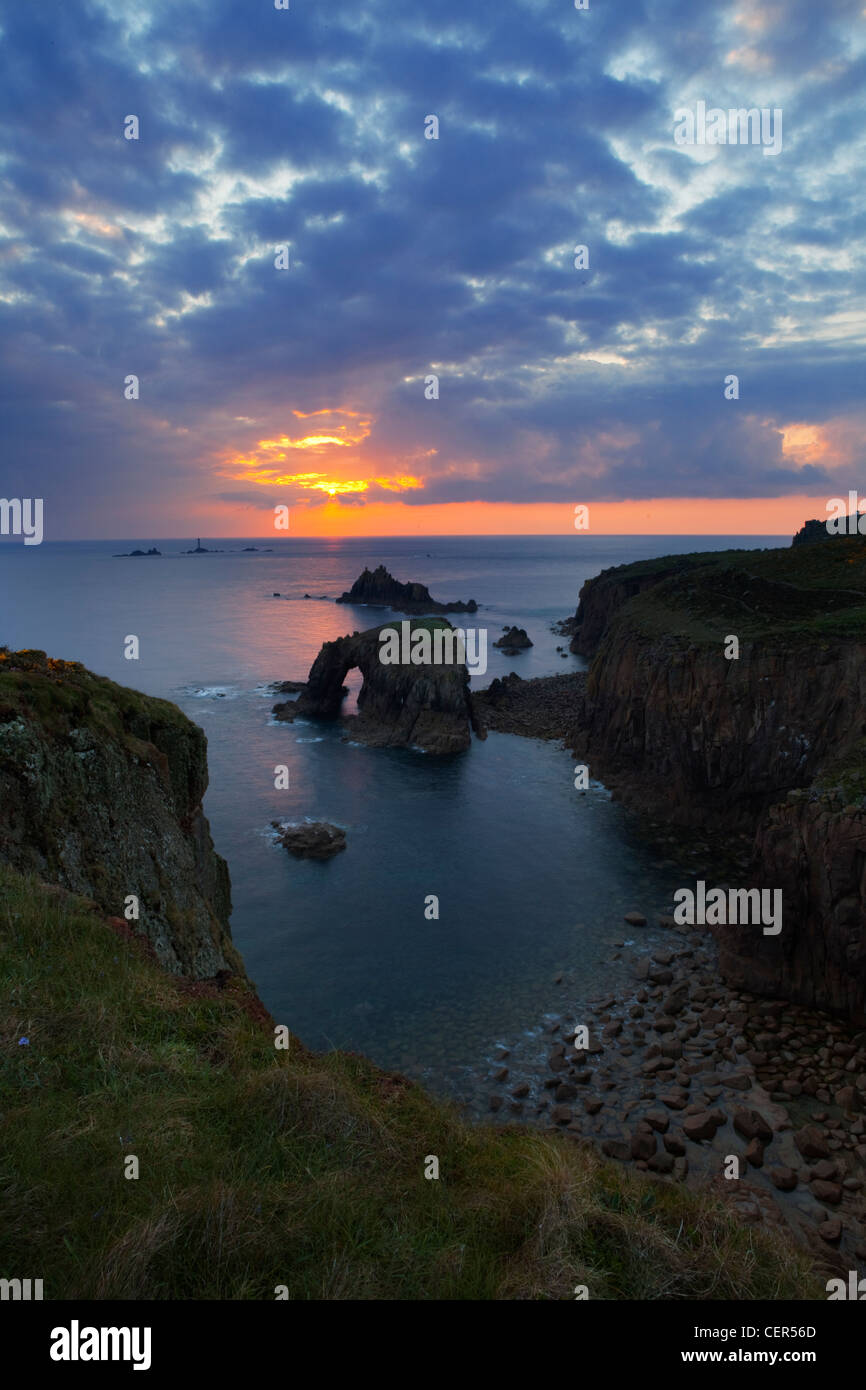 Una vista del Land's End (raggiungere il punto più a ovest in Inghilterra) al tramonto con Longships Lighthouse in distanza. Foto Stock