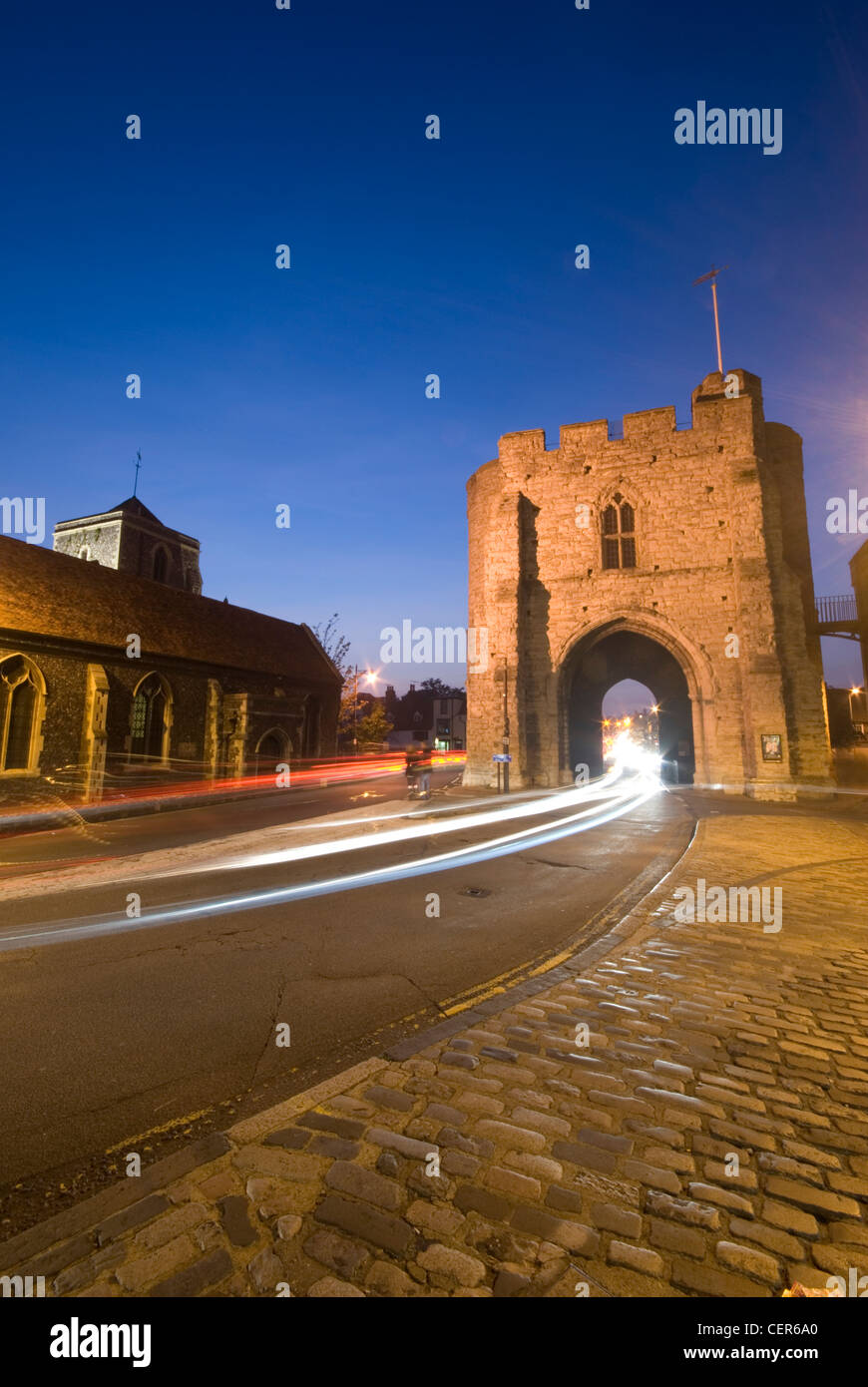 La Torre Westgate in Canterbury illuminata di notte con prove di luce dal traffico in transito. Foto Stock