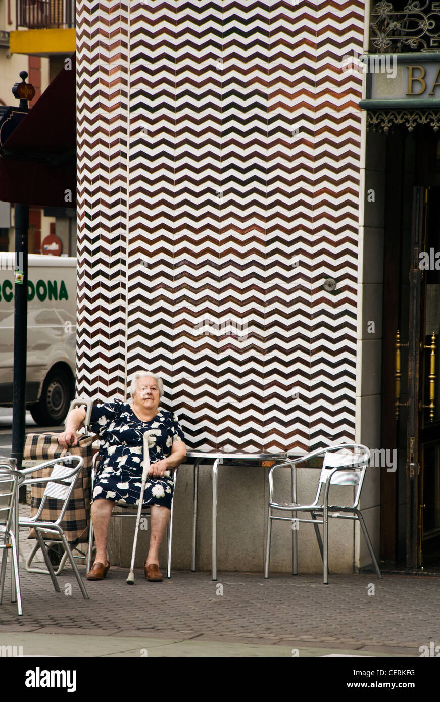 Anziani senior donna si siede al di fuori di un cafe con il suo carrello della spesa Foto Stock