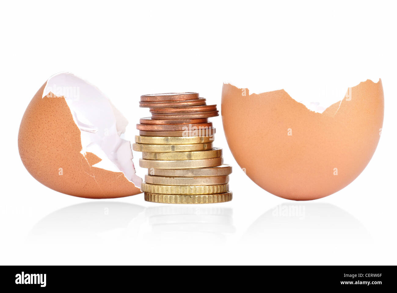 Rotto il guscio delle uova con monete tra su uno sfondo bianco con un'ombra al di sotto Foto Stock