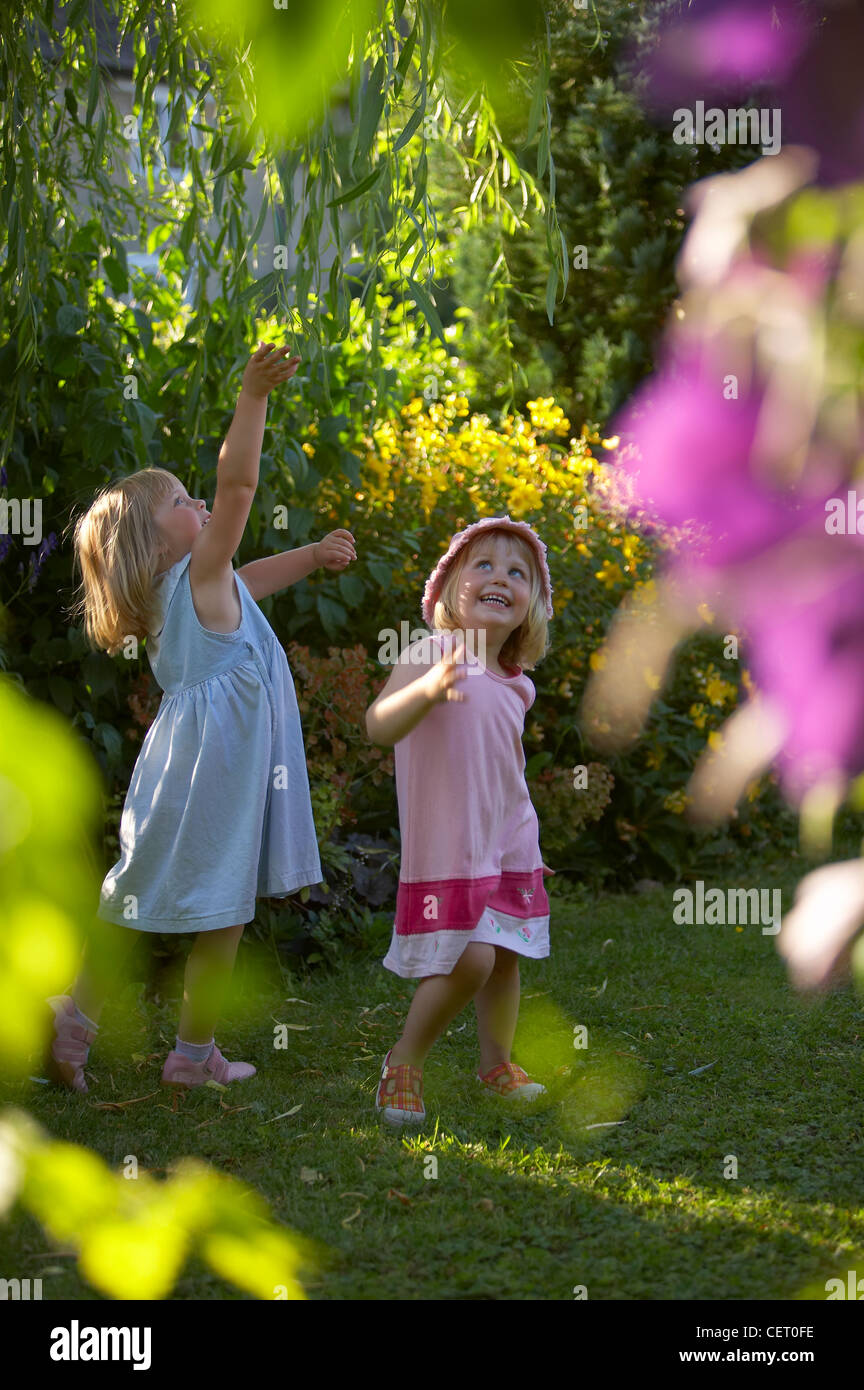 Bambini piccoli (ragazze) giocando nel giardino, Dorset, England, Regno Unito Foto Stock