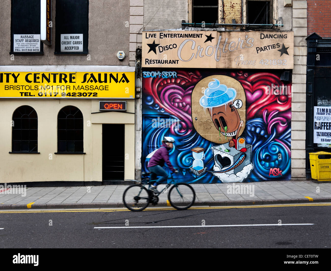 Ciclista passato di equitazione graffiti su Bristol intavolato shop. Foto Stock