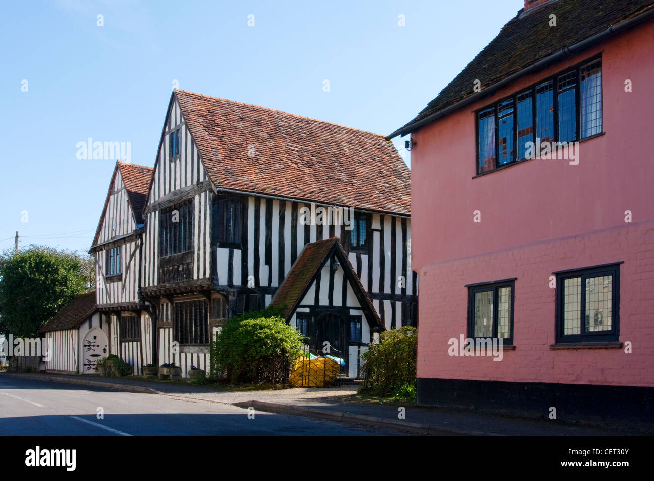 Metà storico-case con travi di legno con una strada nel villaggio di Stratford St Mary. Foto Stock