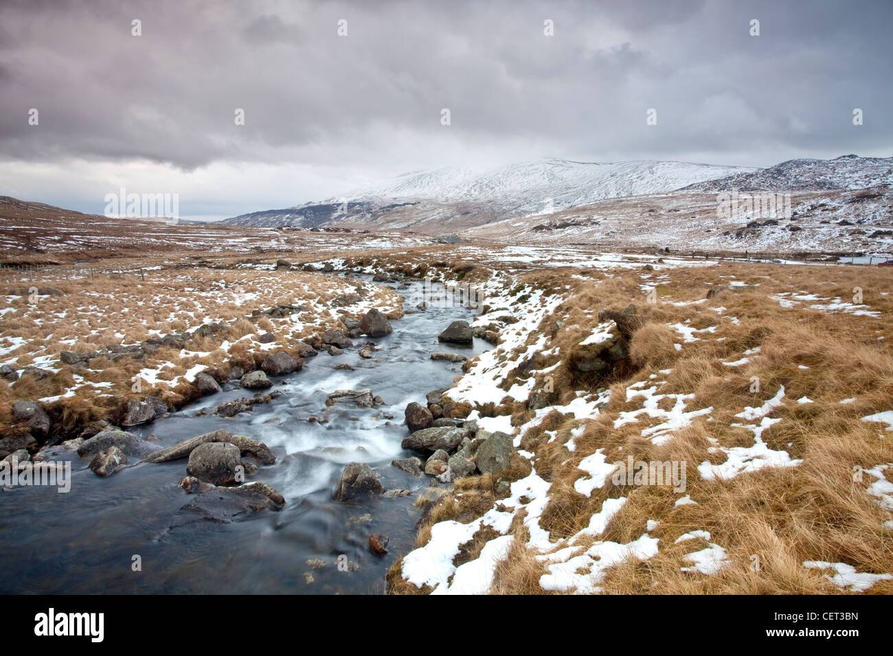 L'acqua che scorre verso il basso dalla montagna su rocce nel Parco Nazionale di Snowdonia in inverno. Foto Stock