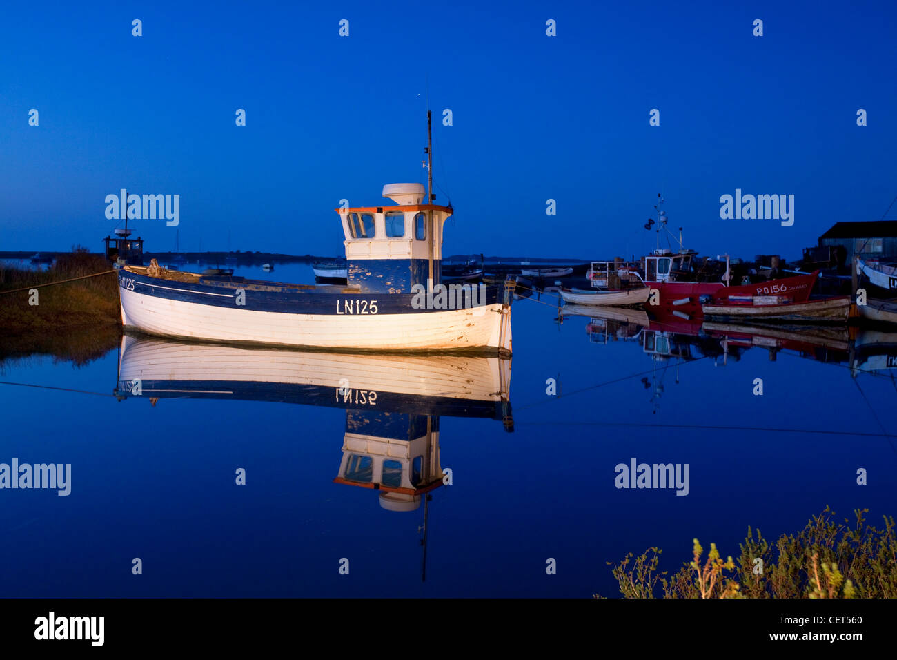 Barche da pesca si riflette ancora in acqua durante la notte sulla costa di Norfolk. Foto Stock