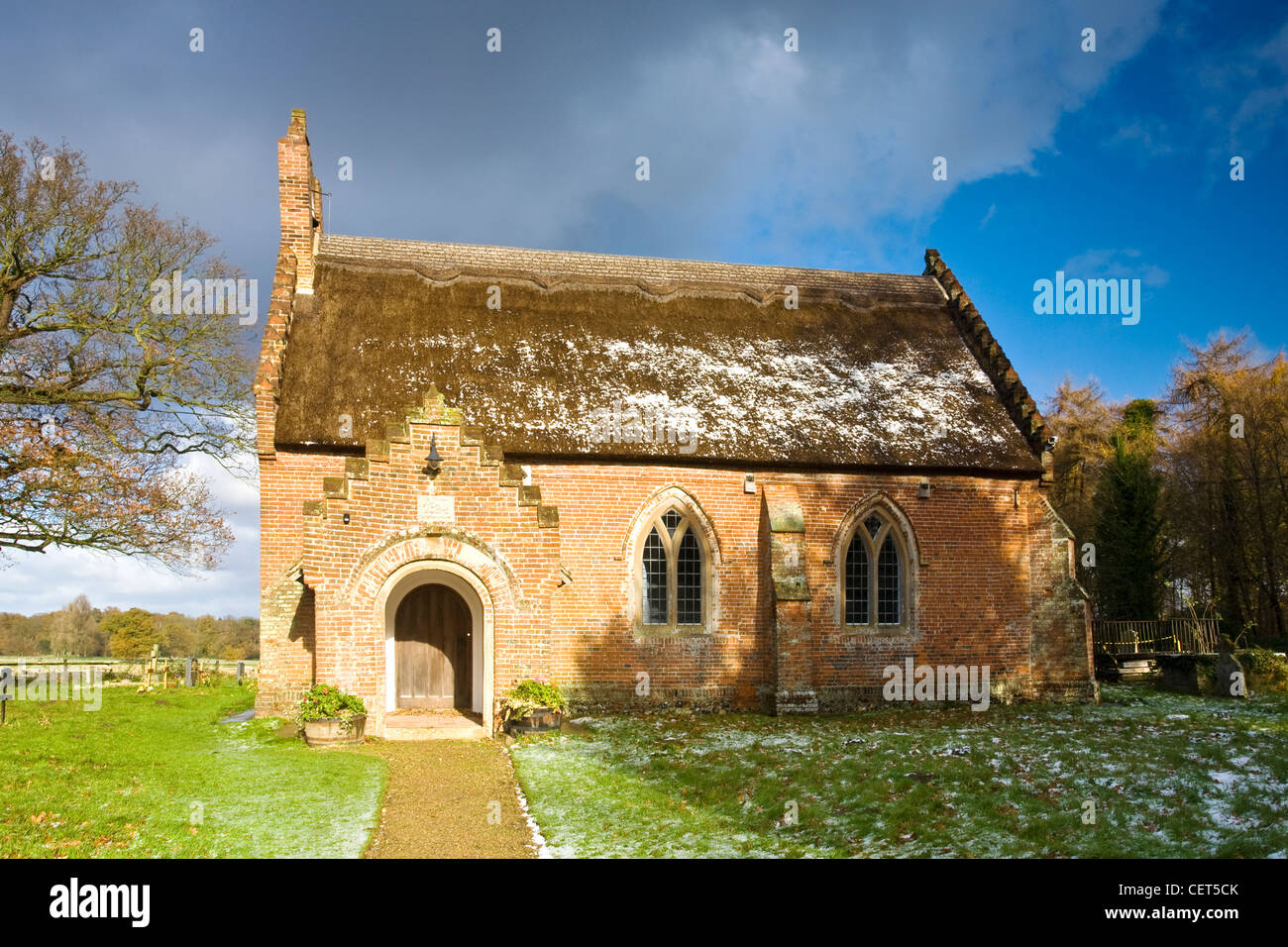 Luce neve sul tetto di paglia del XVII secolo la chiesa di San Pietro, Hoveton. Foto Stock