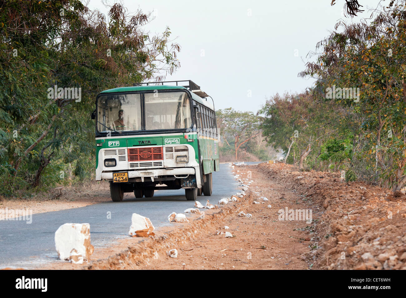 Indian bus / pullman passando per le riparazioni stradali in zone rurali campagna indiana. Andhra Pradesh, India Foto Stock