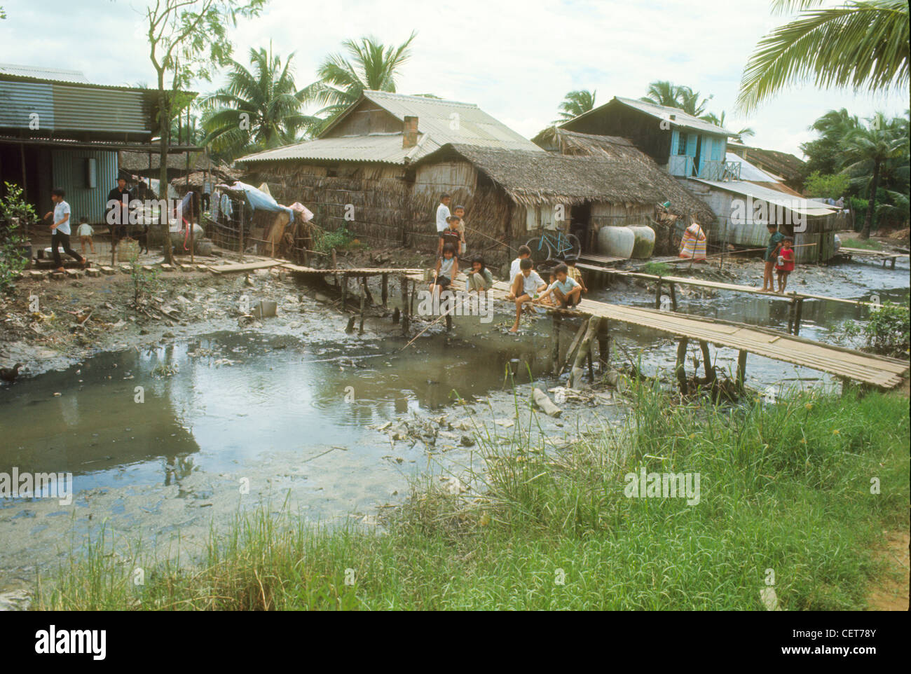 Villaggio accanto al fiume a bassa marea durante la Guerra del Vietnam. I bambini giocando Foto Stock