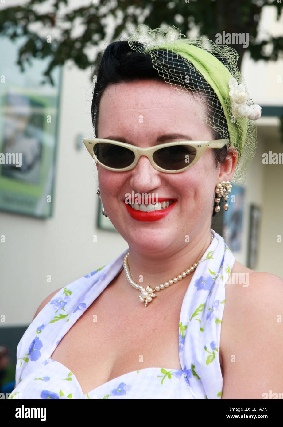 Donna con rossetto rosso, retina per capelli e occhiali alato a Goodwood. Foto Stock