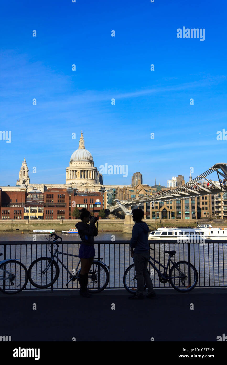 Una giovane coppia di scattare foto attraverso il fiume Tamigi di fronte St.la Cattedrale di San Paolo a Londra, Regno Unito. Foto Stock