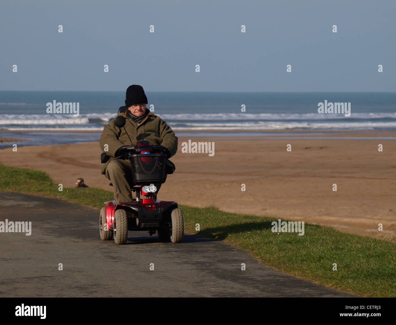 Il vecchio uomo su una mobilità scooter in spiaggia, Bude, Cornwall, Regno Unito Foto Stock
