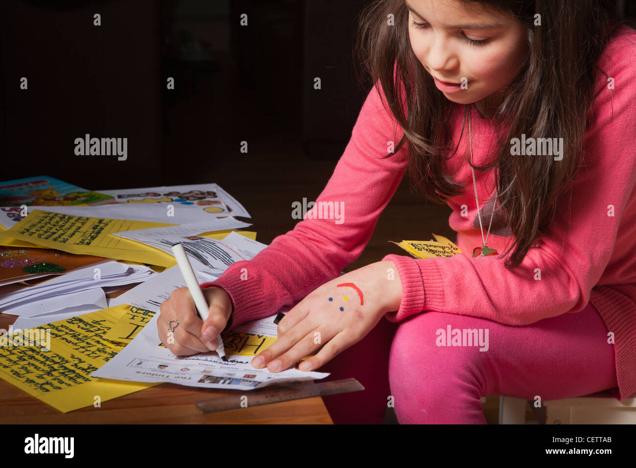 Schoolgirl lavorando su un progetto scolastico a casa da soli Foto Stock