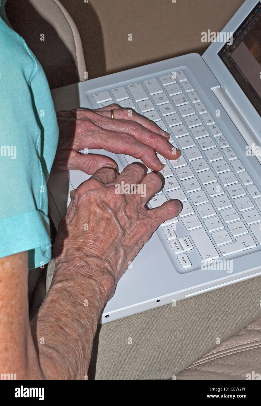 Le mani di una signora anziana usando un computer portatile Foto Stock