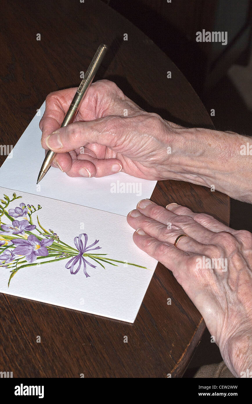 Le mani di una signora di scrivere un biglietto di auguri, UK. Foto Stock
